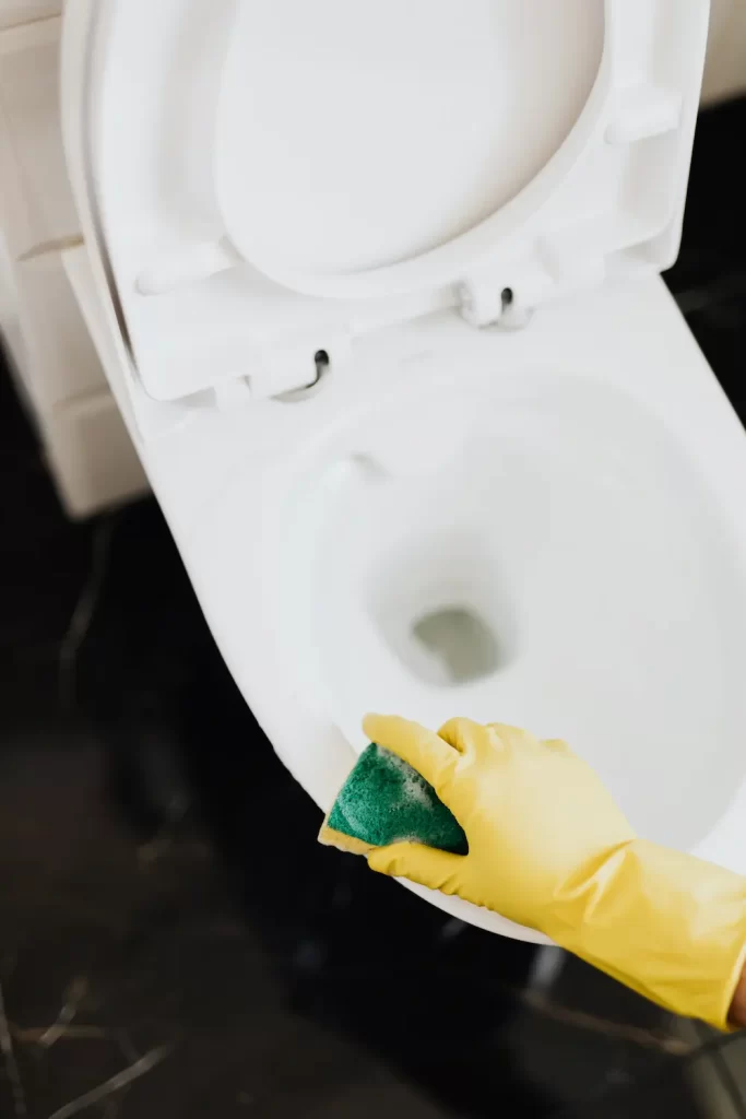 Gloved hand cleaning toilet