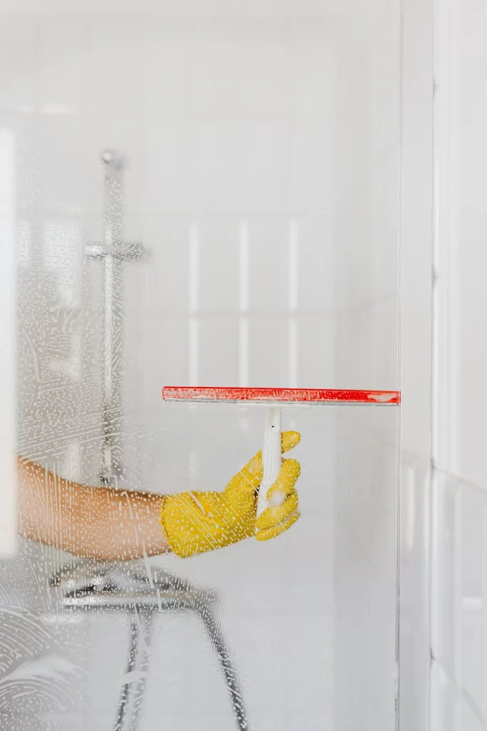 Person cleaning shower door with squeegee