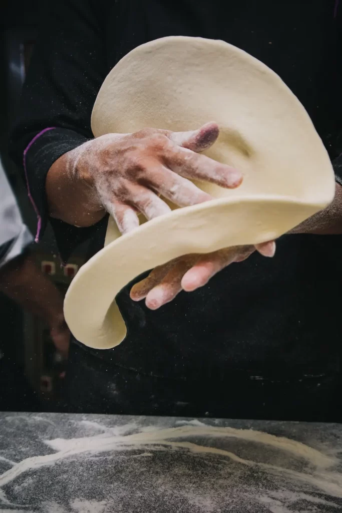 person flipping pizza dough