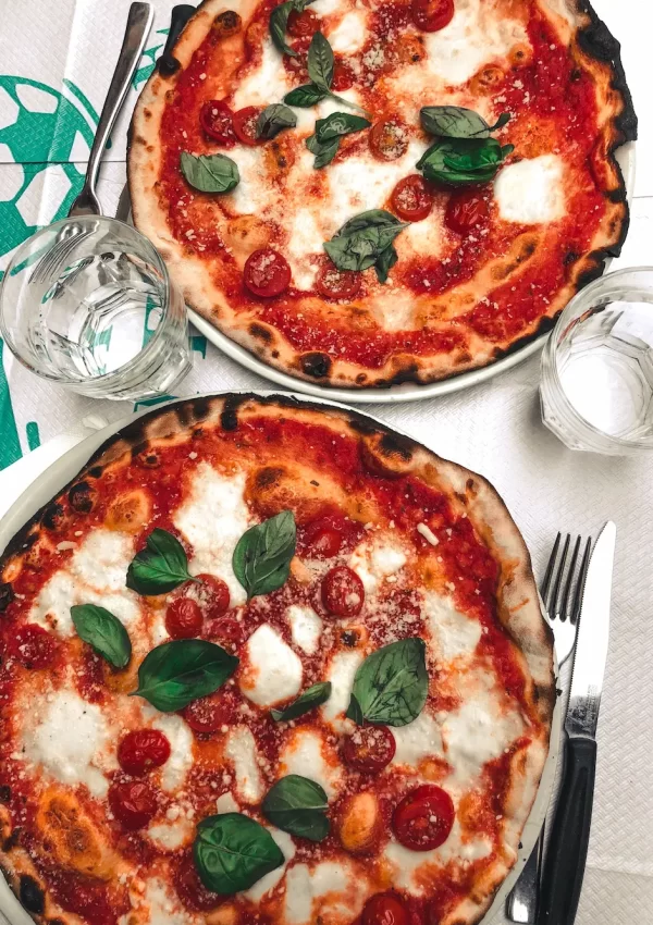 two whole pizzas next to each other on plates