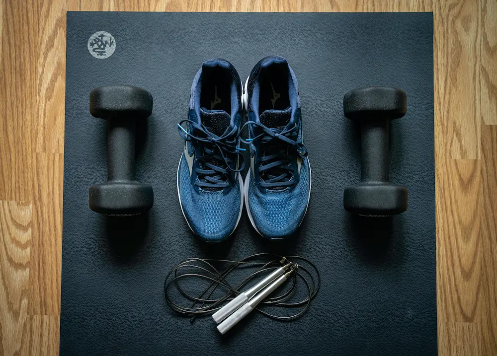 tennis shoes and dumbbells on yoga mat