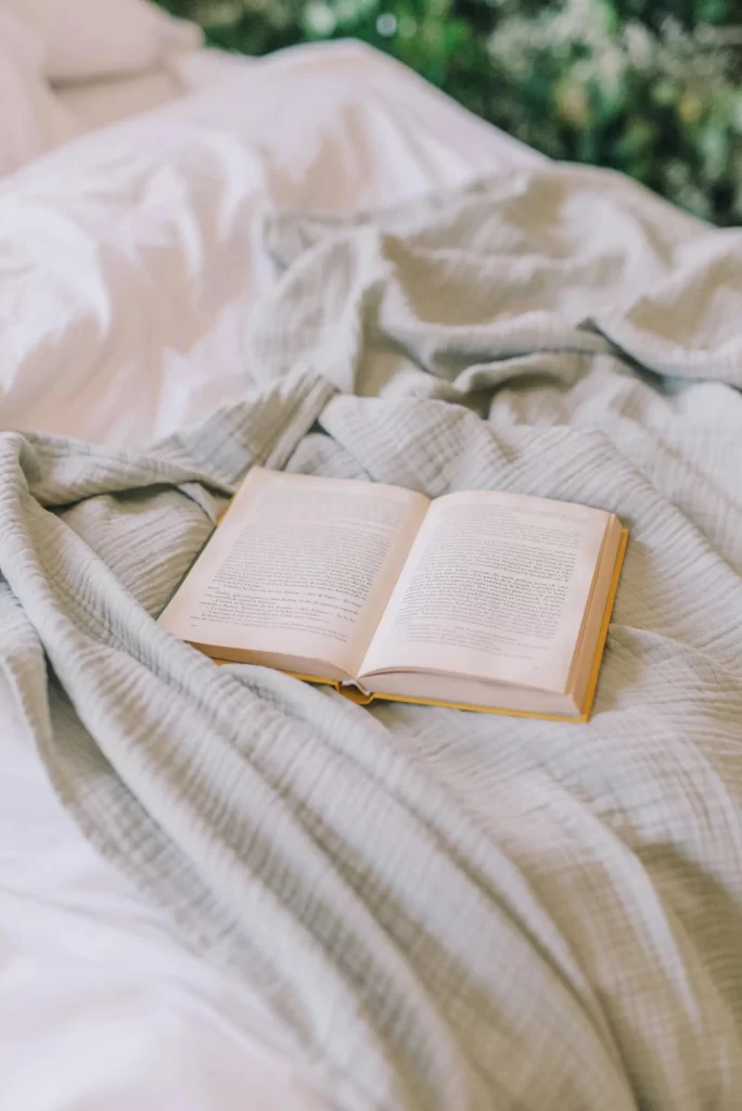 book sitting on top of a blanket on bed